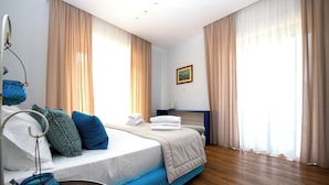 A modern bedroom with a bed, curtains, a bedside table, and a wall-mounted picture. - Shabby Chic sea view apartment (Castellammare di Stabia)
