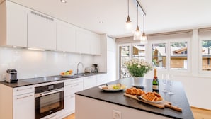 A modern kitchen with white cabinets, a black countertop, and a large window. - Chalet Alpenheim 1 (Lauterbrunnen)