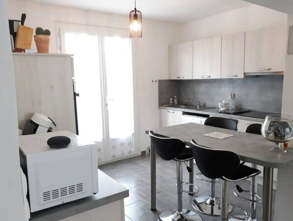 A modern kitchen with white cabinets, a central island with bar stools, and a hanging pendant light. - Air-conditioned house 3 minutes from Carcassonne, with a swimming pool (Pennautier)