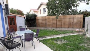 A patio with a table and chairs, a wooden fence, and a grassy area. - Air-conditioned house 3 min from Carcassonne, swimming pool (Pennautier)