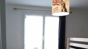 A room with a bunk bed, a desk with a lamp, a window, and a curtain. - Air-conditioned house 3 min from Carcassonne, swimming pool (Pennautier)