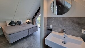 Quarto moderno com cama, mesa de cabeceira e um espelho grande.