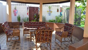 Une terrasse extérieure avec des meubles en osier, un banc à motifs et des plantes en pot.