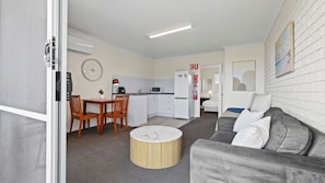 A compact living space with a kitchenette, a dining area, a sofa, and a bed.