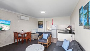 Un espace de vie compact comprenant un coin repas, un canapé et une kitchenette.