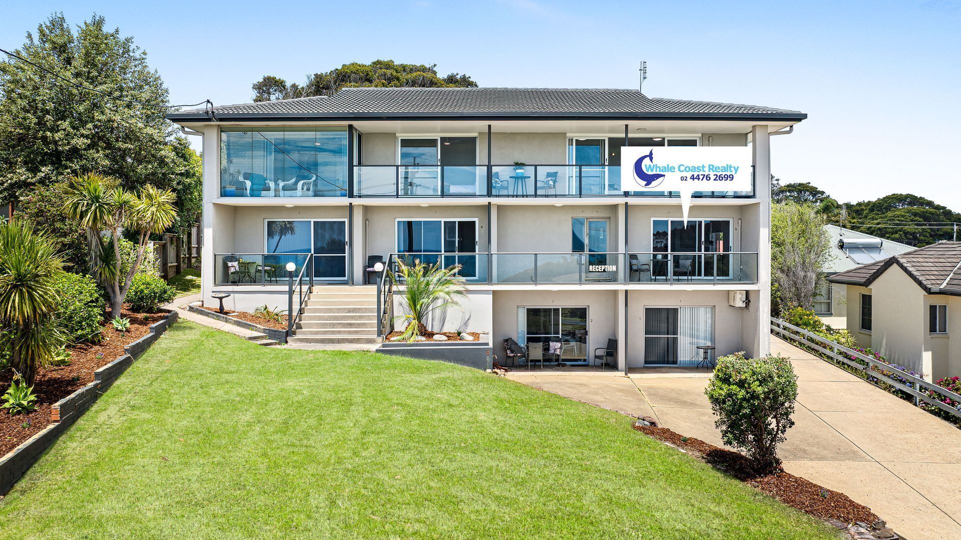 A two-story building with a reception area on the ground floor and a balcony with seating.