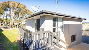 A small, single-story building with a balcony, satellite dish, and a clear view of the surrounding area.