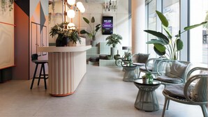 Un interior moderno con mostrador de recepción, zona de estar y ventanas amplias.