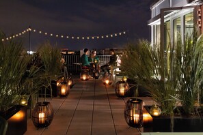 A rooftop terrace with string lights, potted plants, and candle lanterns. - BaseCamp Hotel Dortmund (Dortmund)