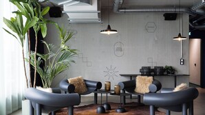 Un área de descanso moderna con sofás negros, una mesa de centro y una planta grande en maceta.