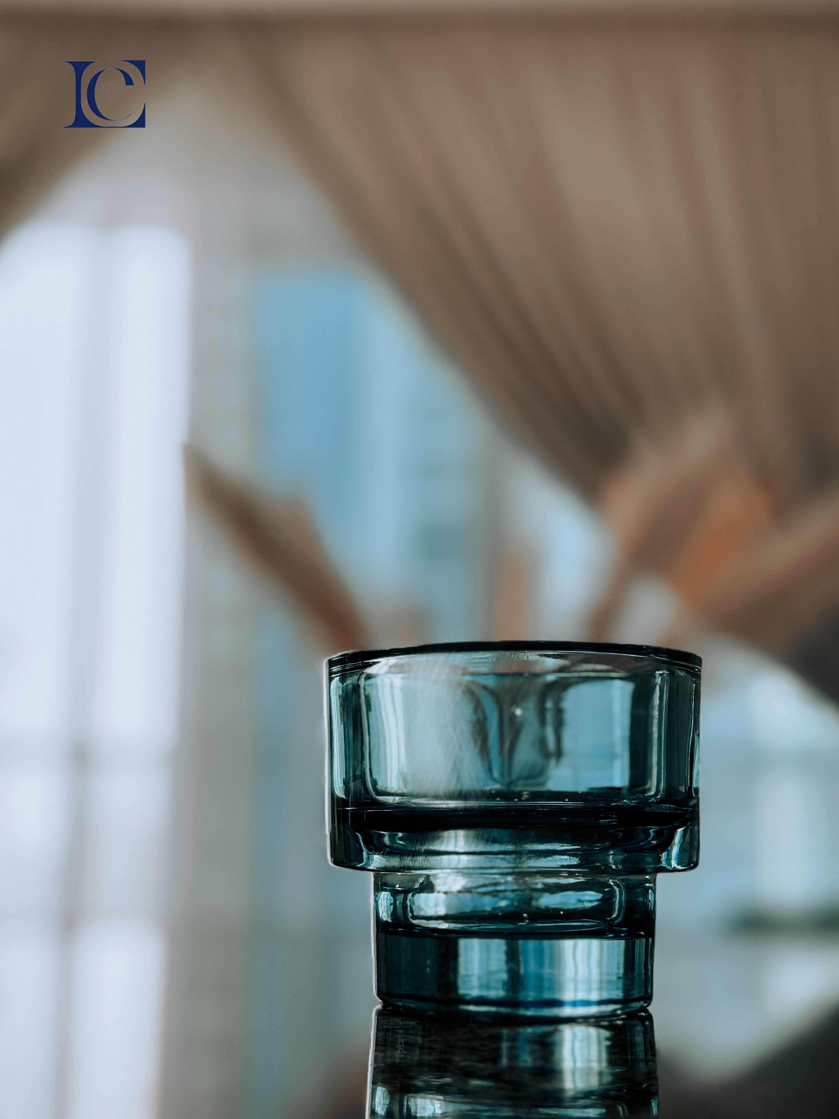 A clear glass bottle with a blue tint, positioned in the foreground with a blurred background.