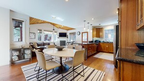 A modern kitchen with wooden cabinets, a dining area with a round table and chairs, and a fireplace. - Pet-Friendly, 5-Star Home, Private Hot Tub, 2-Car Garage, Walk to The Village (Mammoth Lakes)