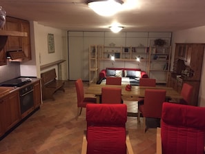 A dining area with a wooden table and red chairs, a kitchen with wooden cabinets, and a bookshelf with various items. - "VILLINO MIRALAGO" BEAUTIFUL VIEW (Torno)