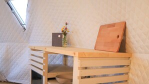 A small, cozy attic room with a wooden desk, a metal bucket, and a window. - Enjoy Lofoten Glamping (Vestvågøy)