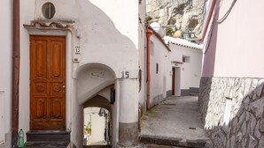 Une rue étroite avec une porte en bois et une petite arche menant à un bâtiment.