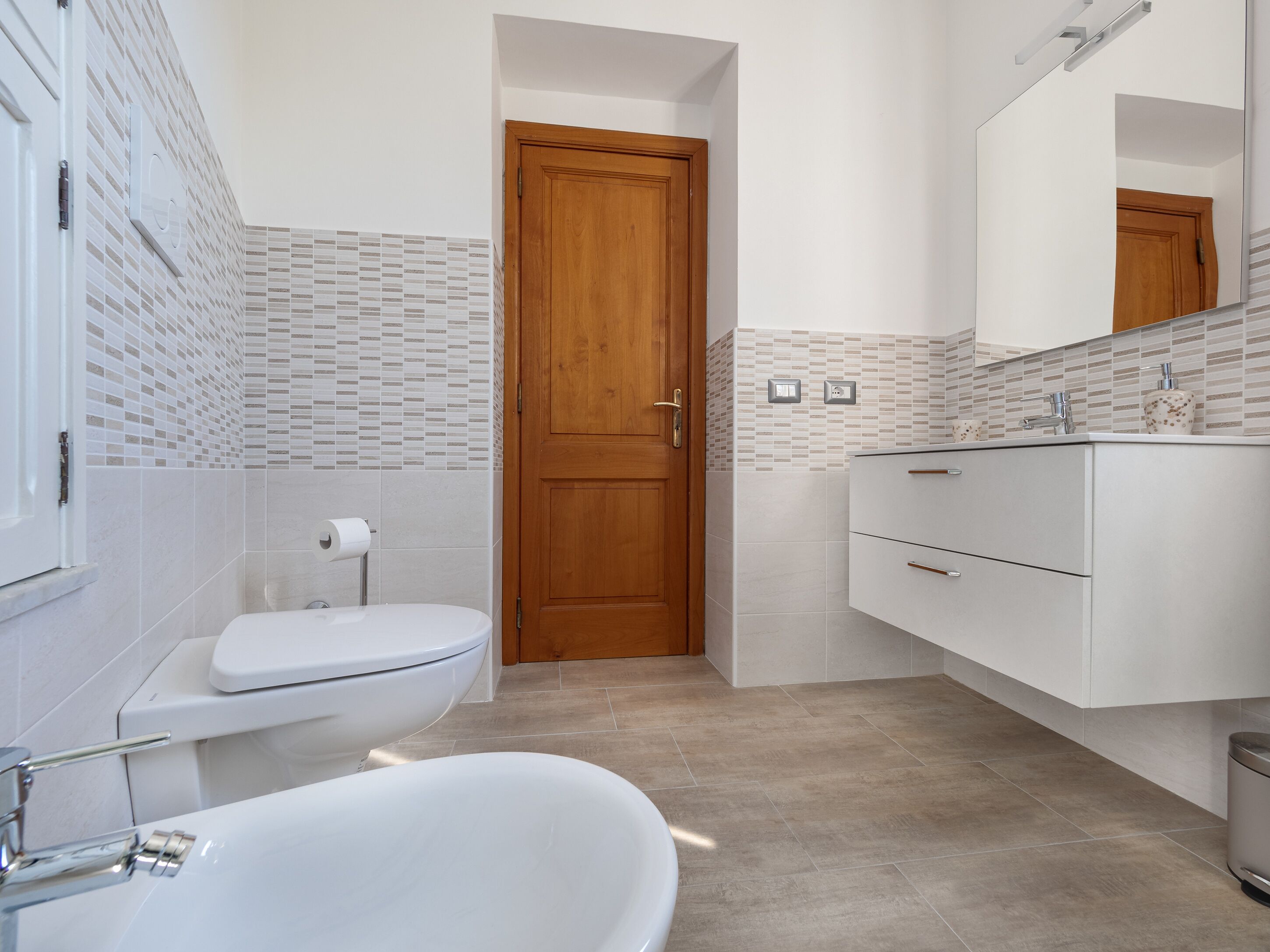Ein modernes Badezimmer mit Toilette, Waschbecken und Badewanne.