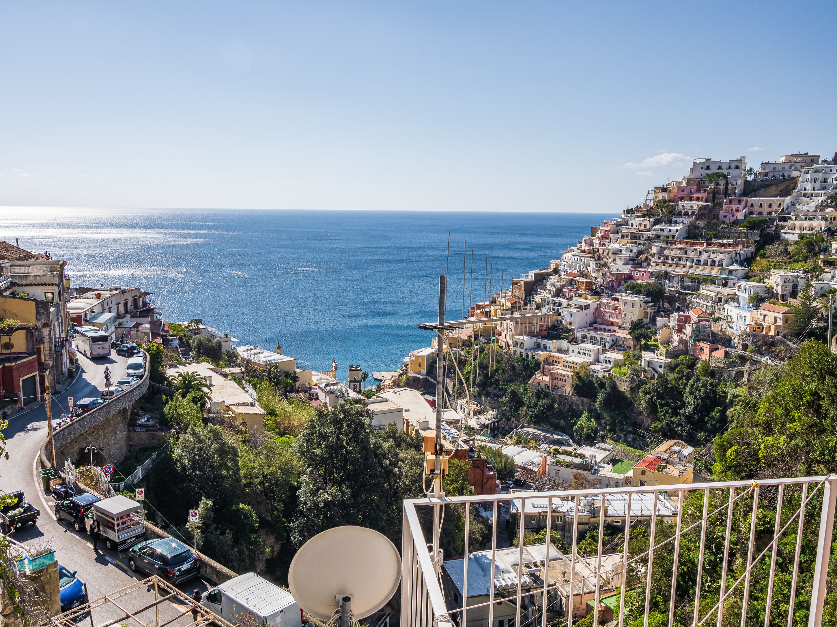 Une ville côtière avec une route sinueuse, une antenne parabolique et des bâtiments dotés de balcons donnant sur la mer.