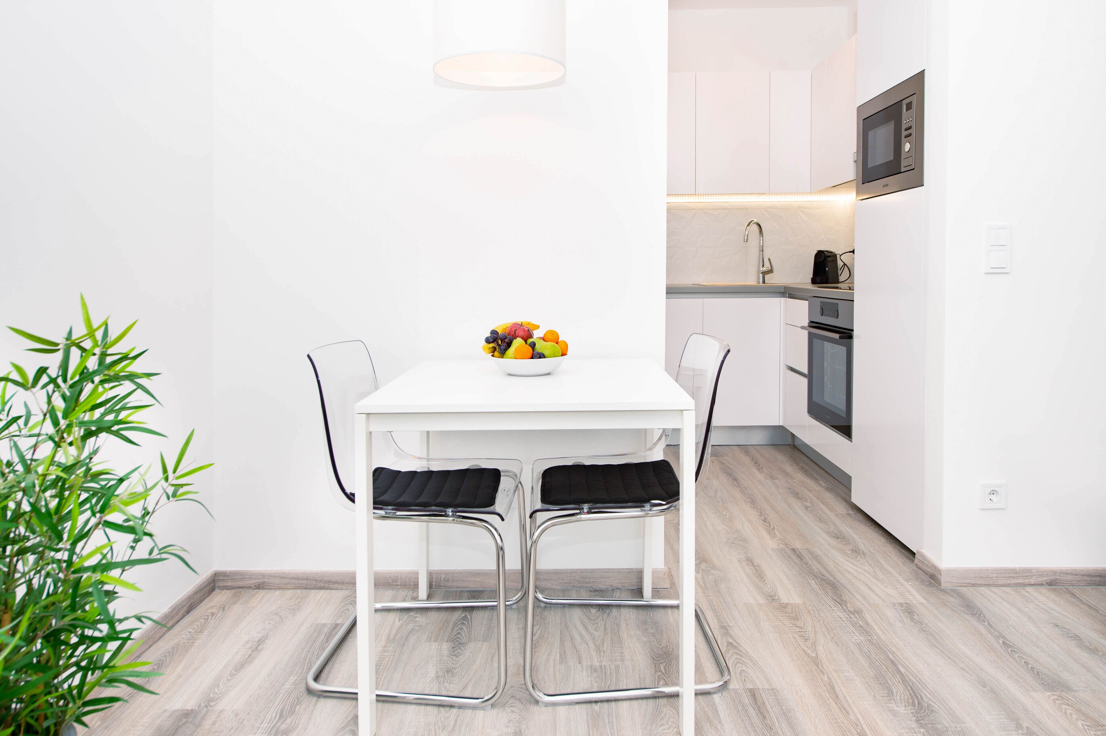 A modern kitchen with white cabinets, a microwave, and a sink.