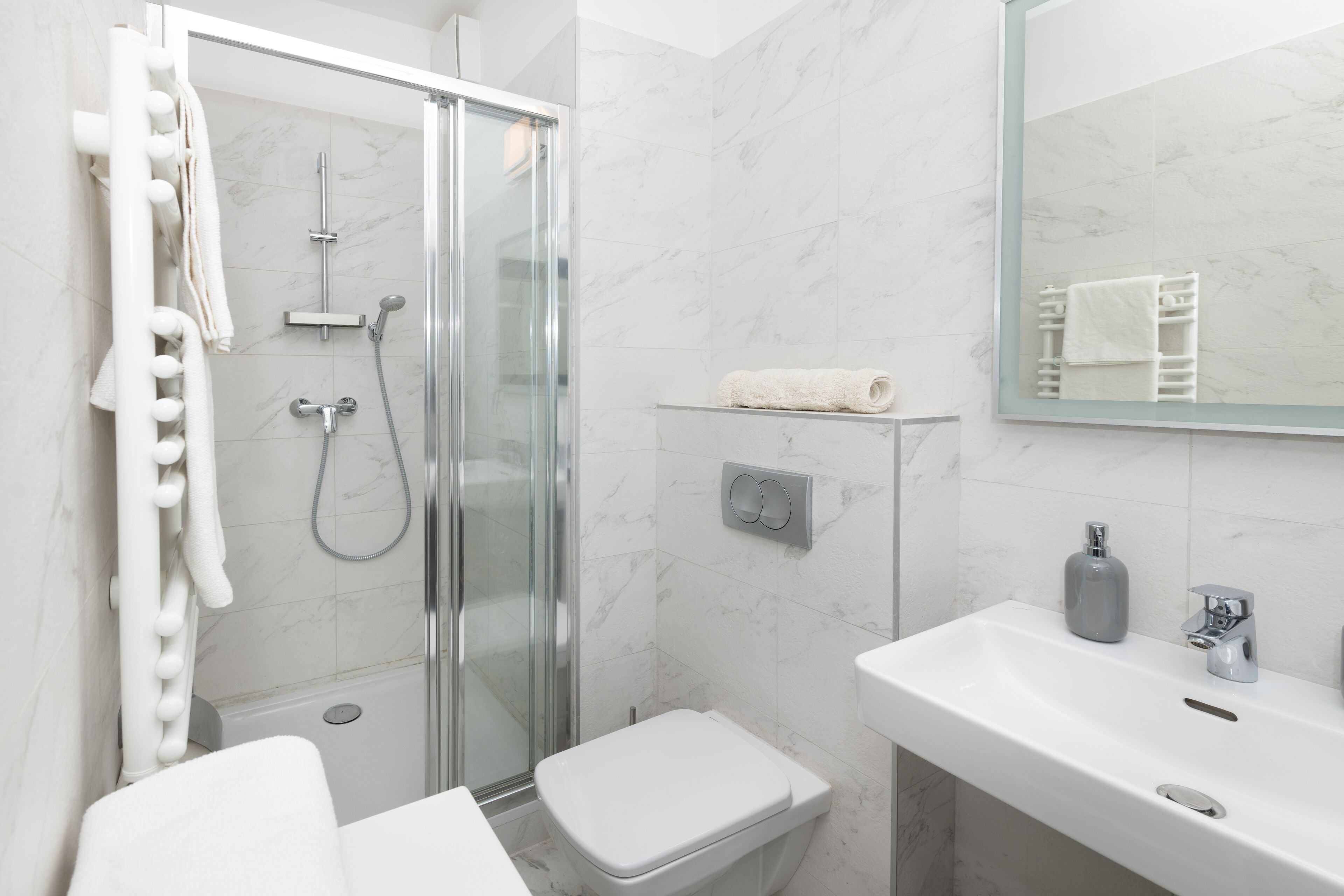 Un baño moderno con ducha de vidrio, lavamanos blanco y retrete.