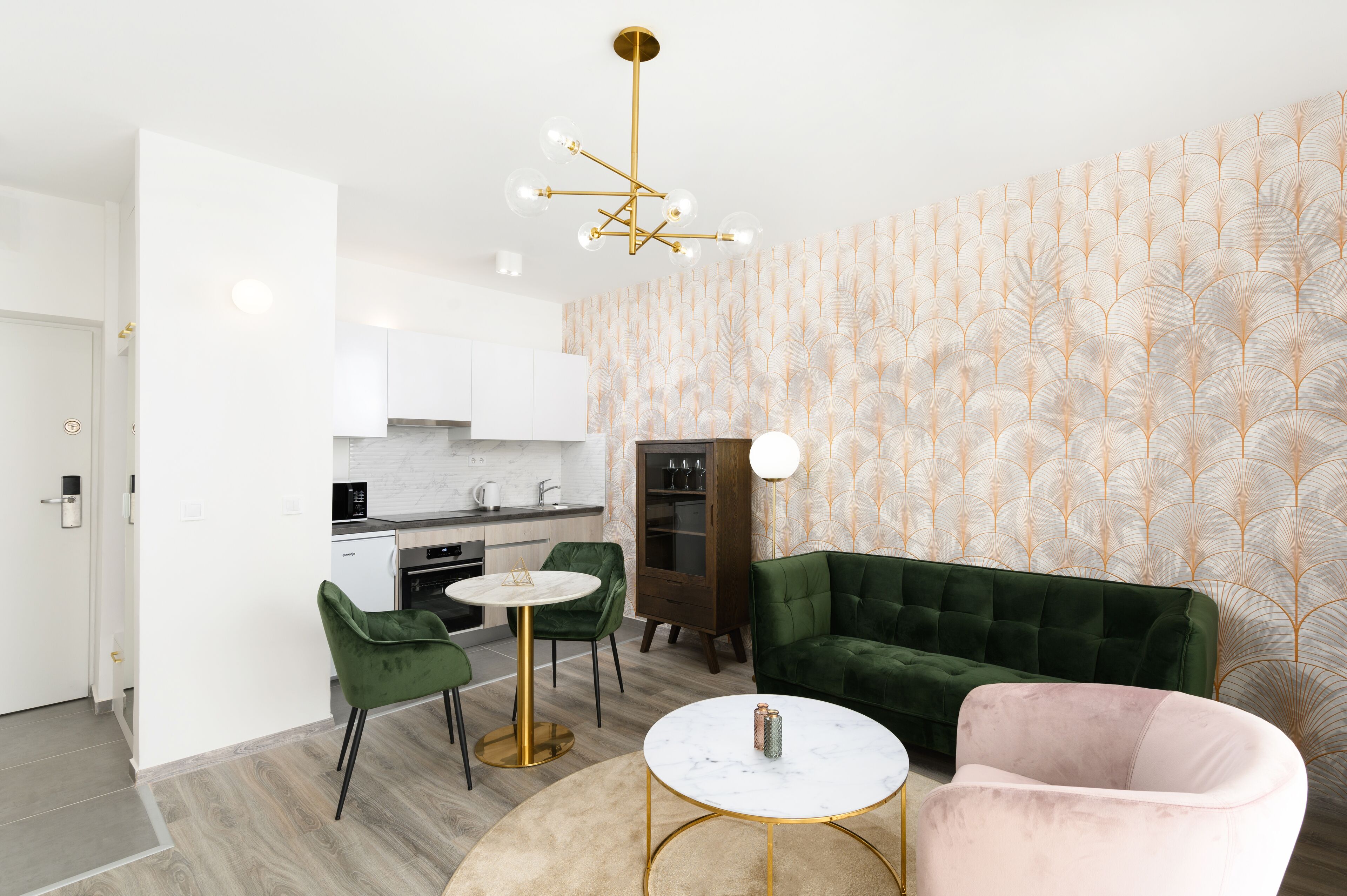 A modern kitchen with white cabinets, a green sofa, and a round table.