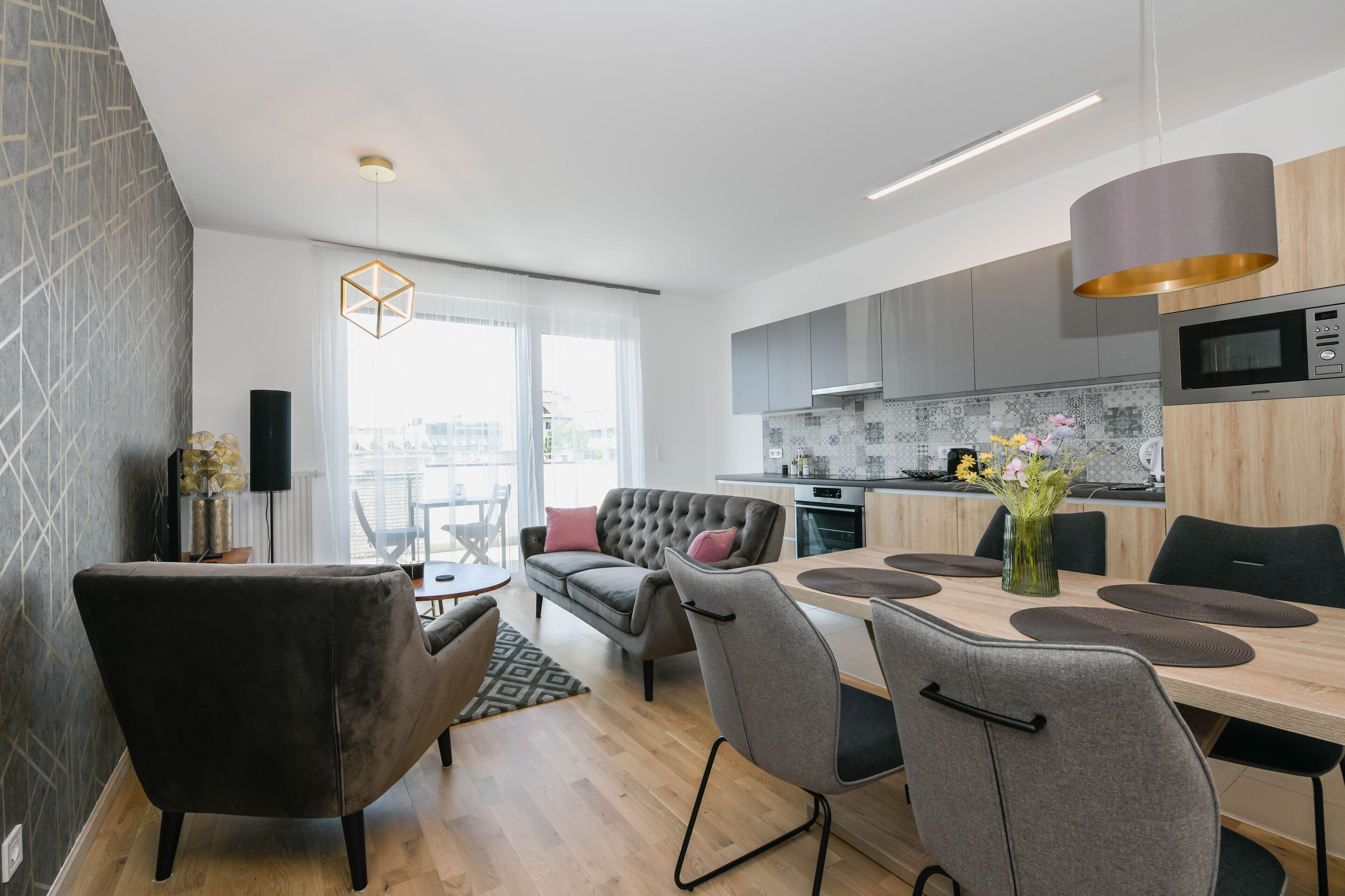 Une cuisine moderne avec des meubles gris, un four à micro-ondes et un coin repas comprenant une table et des chaises.