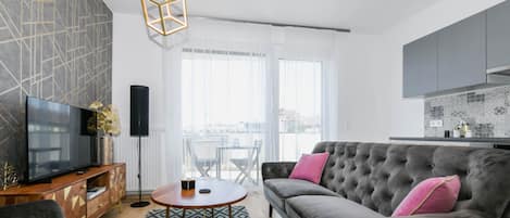 A modern living room with a grey sofa, a wooden coffee table, and a large flat-screen TV.