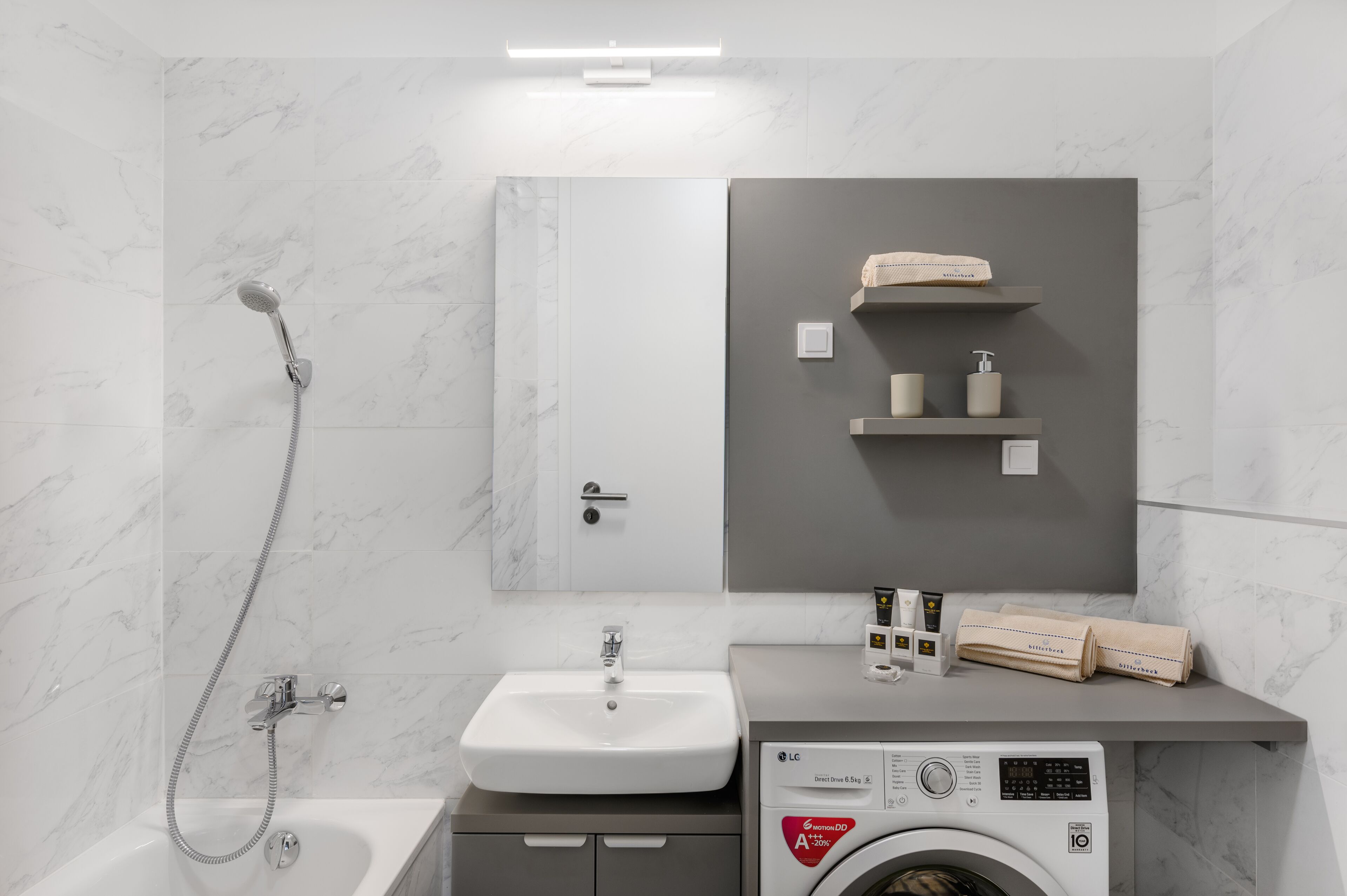 Ein modernes Badezimmer mit Waschbecken, Spiegel, Handtuchhalter und einer Waschmaschine.
