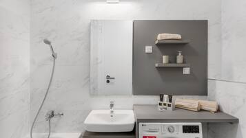 Une salle de bain moderne équipée d’un lavabo, d’un miroir, d’un porte-serviettes et d’un lave-linge.