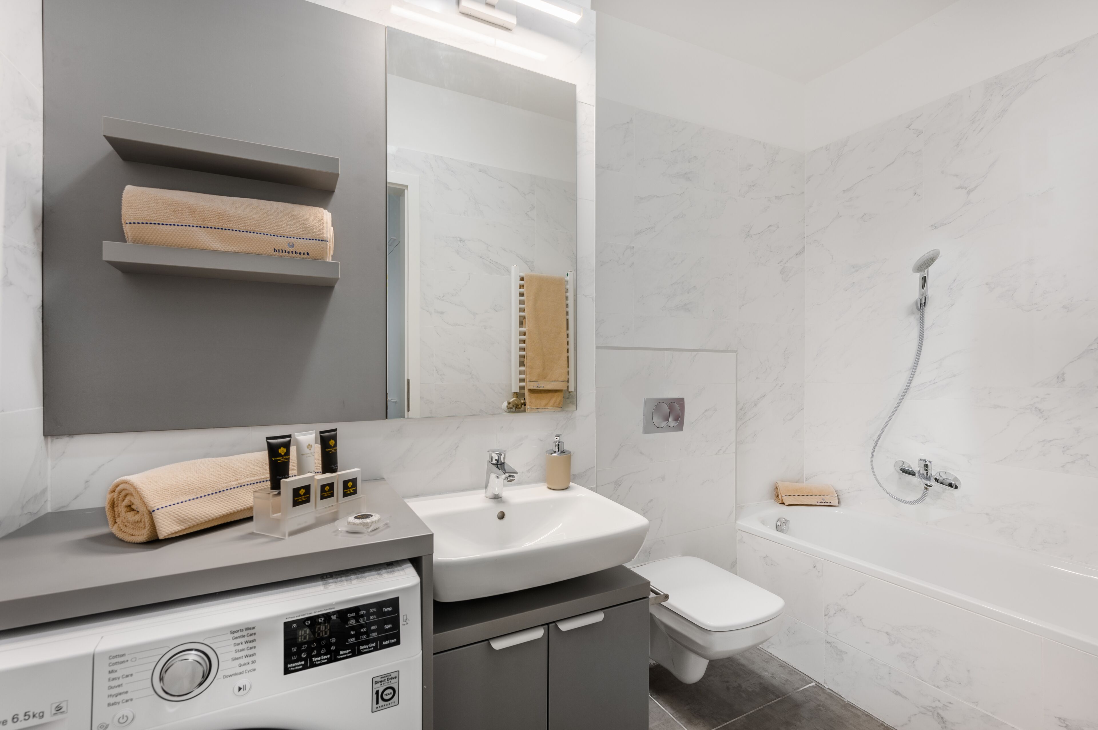 A modern bathroom with a grey vanity, a white sink, a toilet, and a shower.