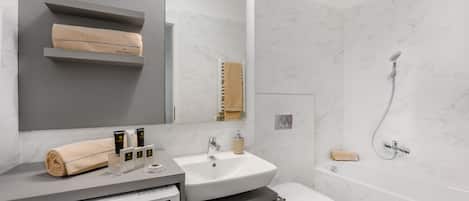 A modern bathroom with a grey vanity, a white sink, a toilet, and a shower.