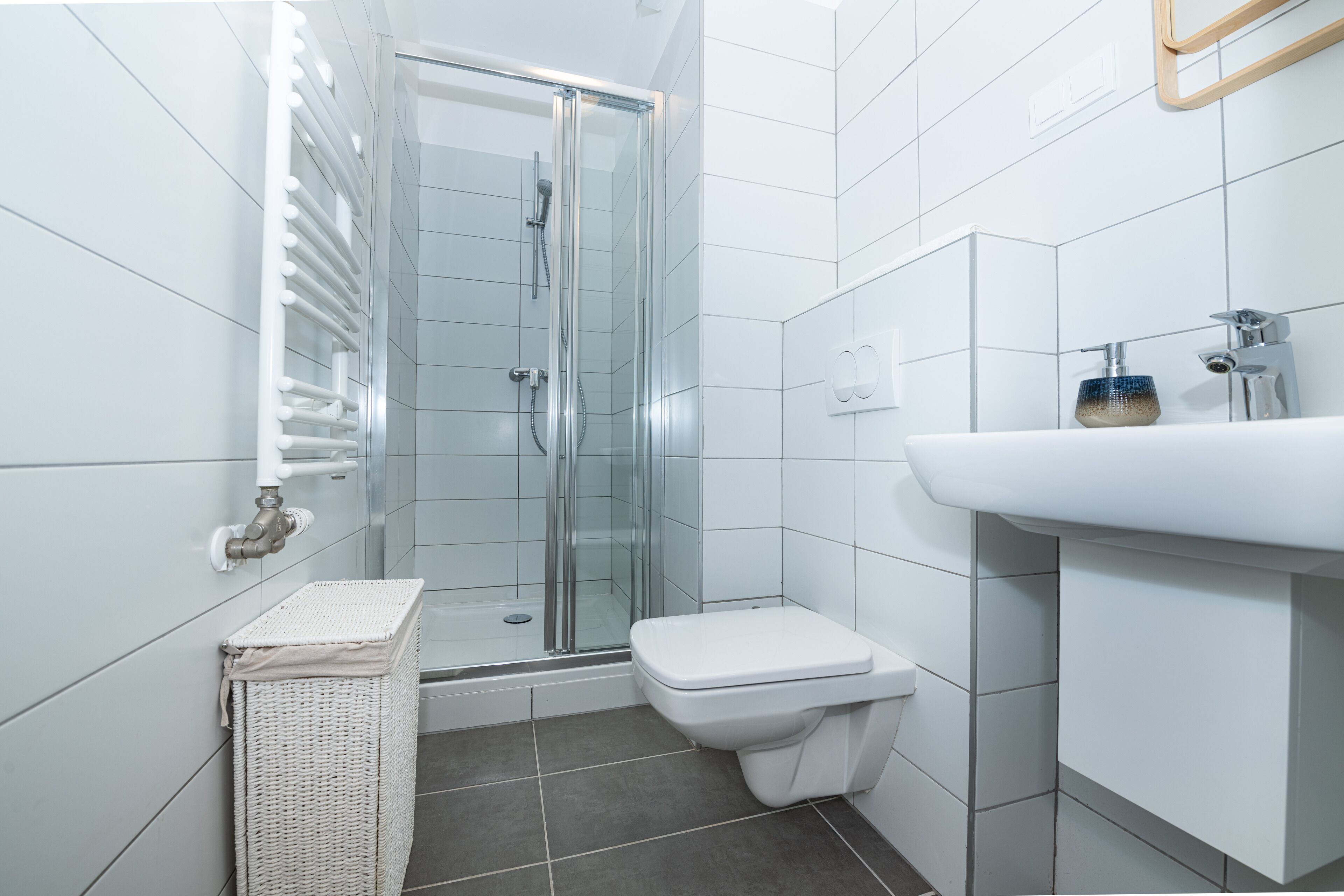 Un baño moderno con cabina de ducha de vidrio, un lavamanos blanco y un inodoro.