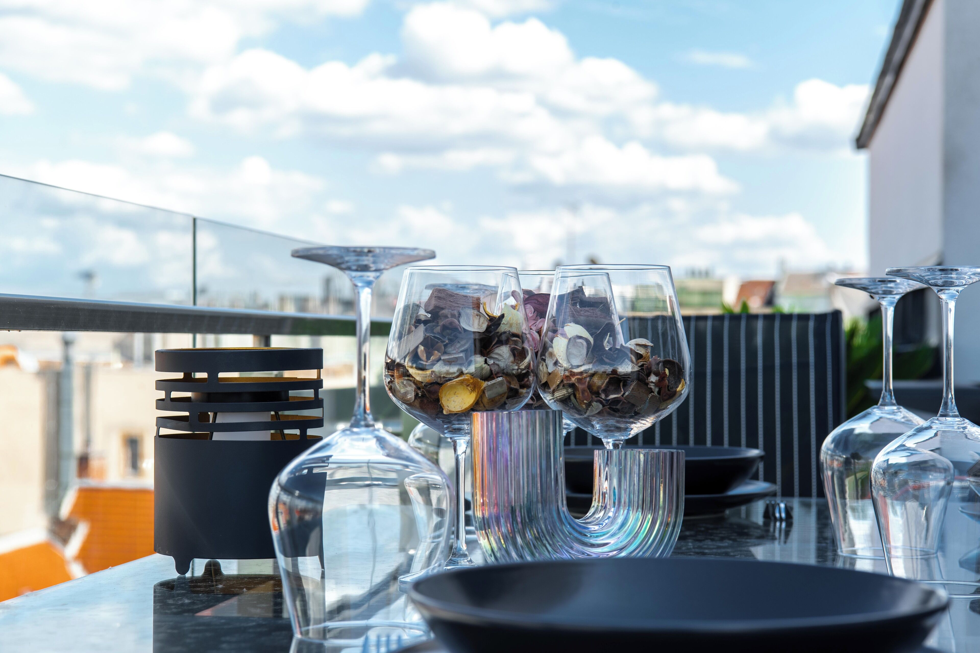 Une table avec des verres à vin et un saladier, disposée à l’extérieur, avec un ciel dégagé en arrière-plan.