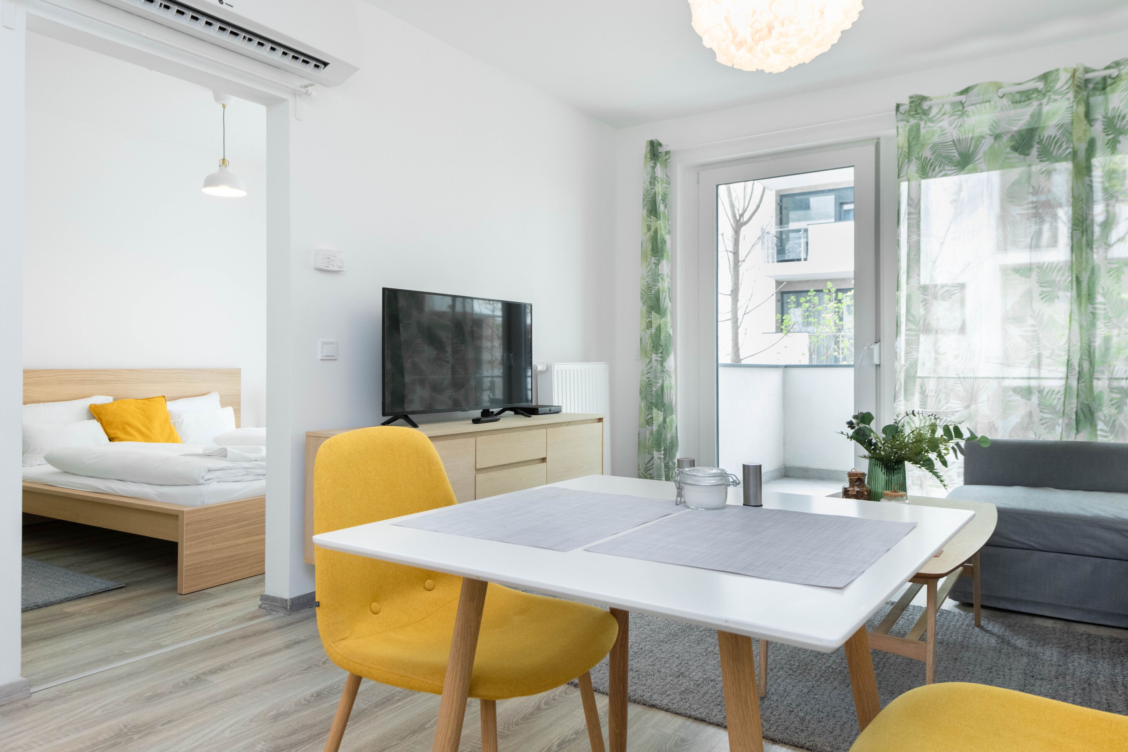 Una habitación de hotel moderna con una cama, una mesa de comedor con sillas, un televisor y un sofá.
