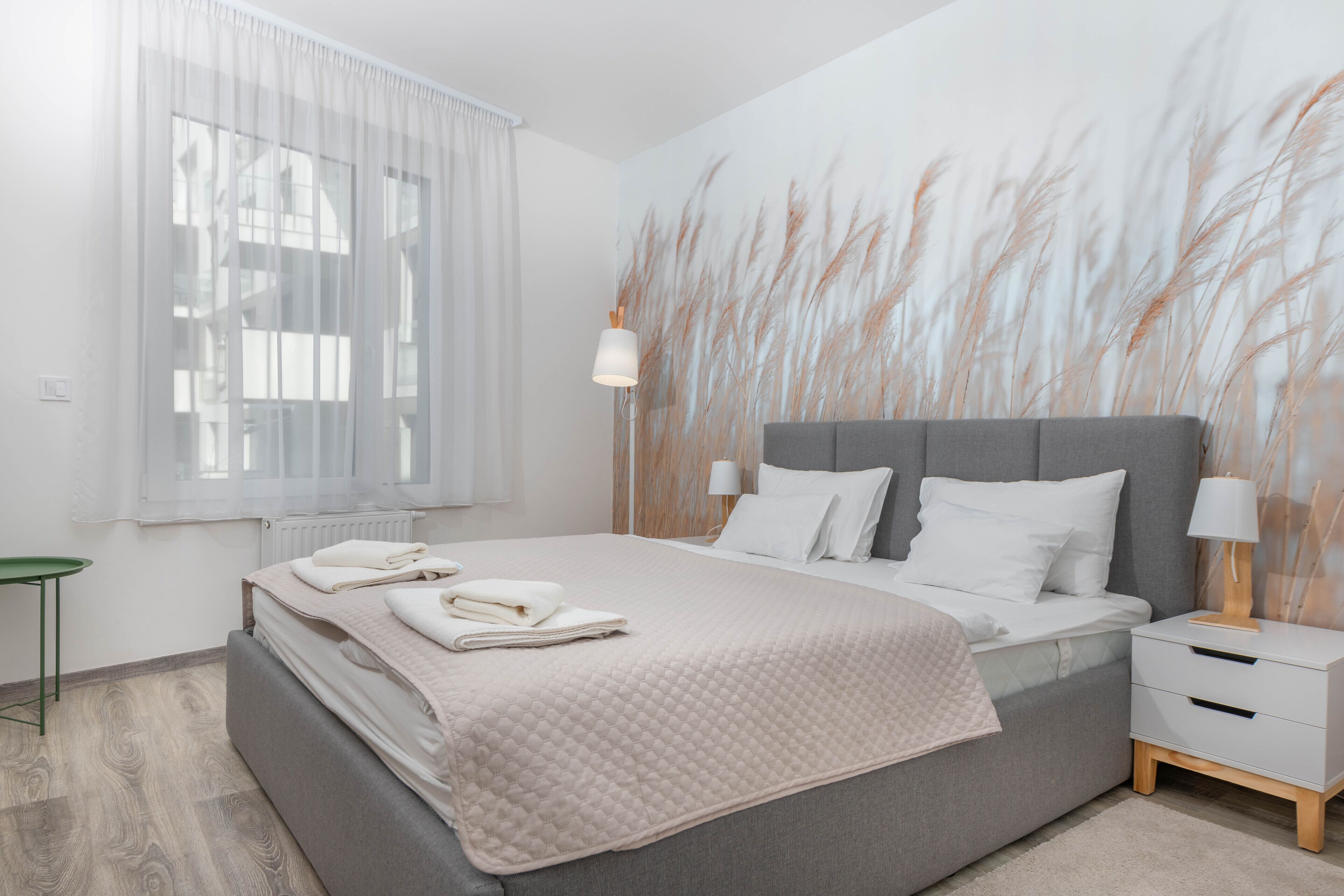 Quarto moderno com cama grande, mesas de cabeceira e painel decorativo na parede.