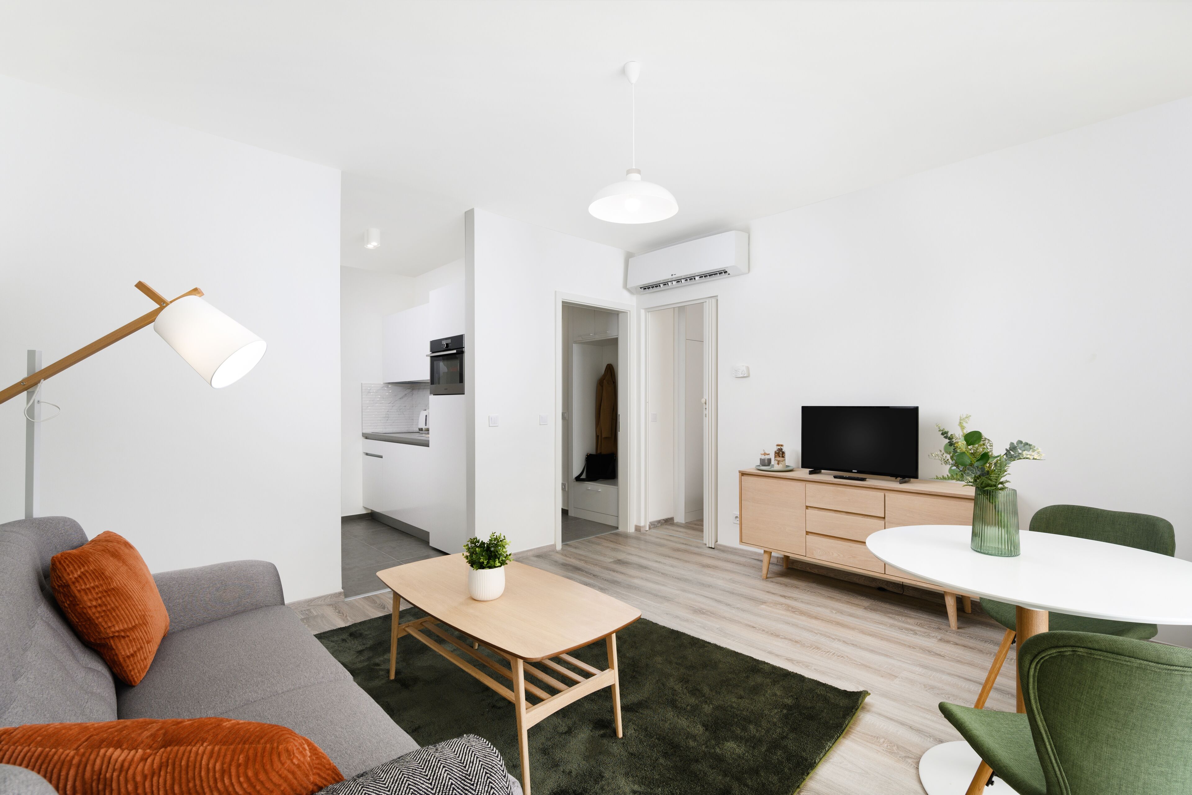 Ett modernt vardagsrum med en soffa, ett soffbord, en tv och en matplats med ett bord och stolar.
