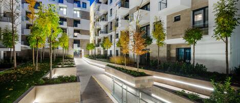 Un moderno condominio con numerosi balconi, un percorso centrale e aree verdi alberate.