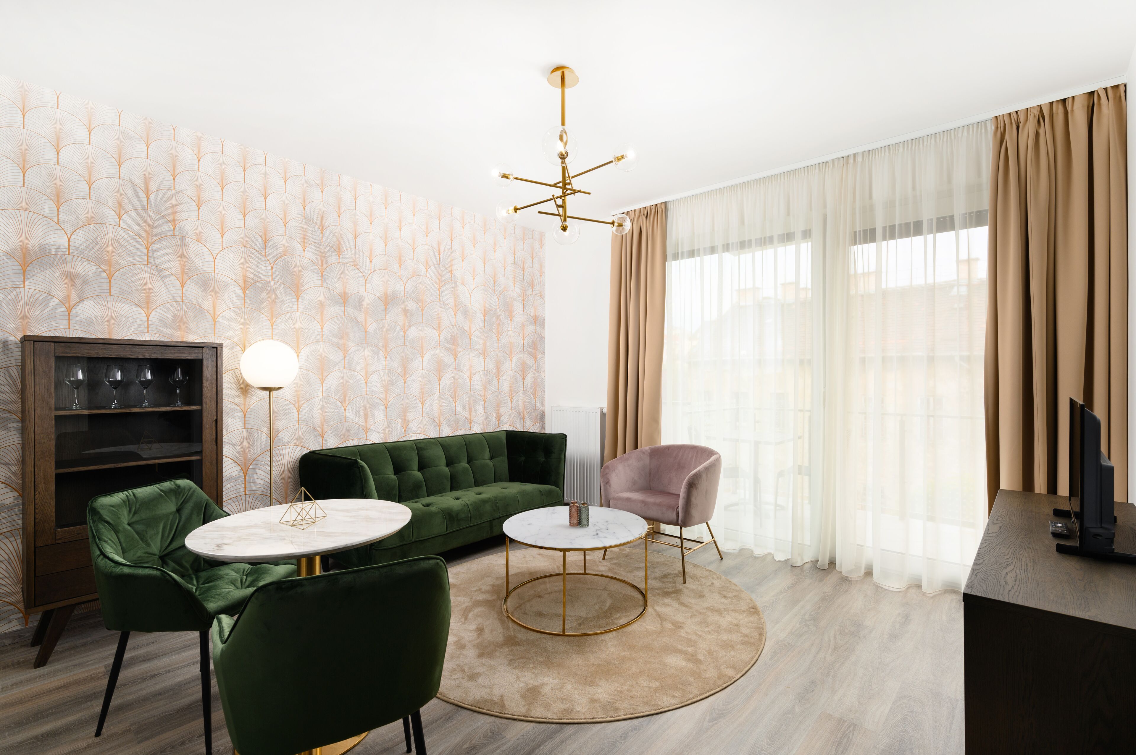Una sala moderna con un sofá verde, una mesa de centro redonda y un sillón rosa.