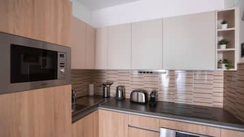 Eine moderne Küche mit Holzausstattung, Mikrowelle aus Edelstahl, Wasserkocher, Toaster und Geschirrspüler.