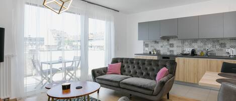 Una sala de estar moderna con un sofá gris, una mesa de centro redonda y una alfombra estampada.