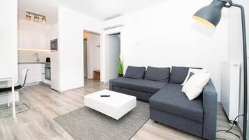 Una sala de estar moderna con un sofá gris, una mesa de centro blanca y una lámpara de pie negra.