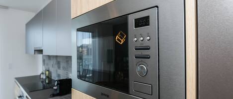 A modern kitchen with a built-in microwave oven, a digital display, and control buttons.