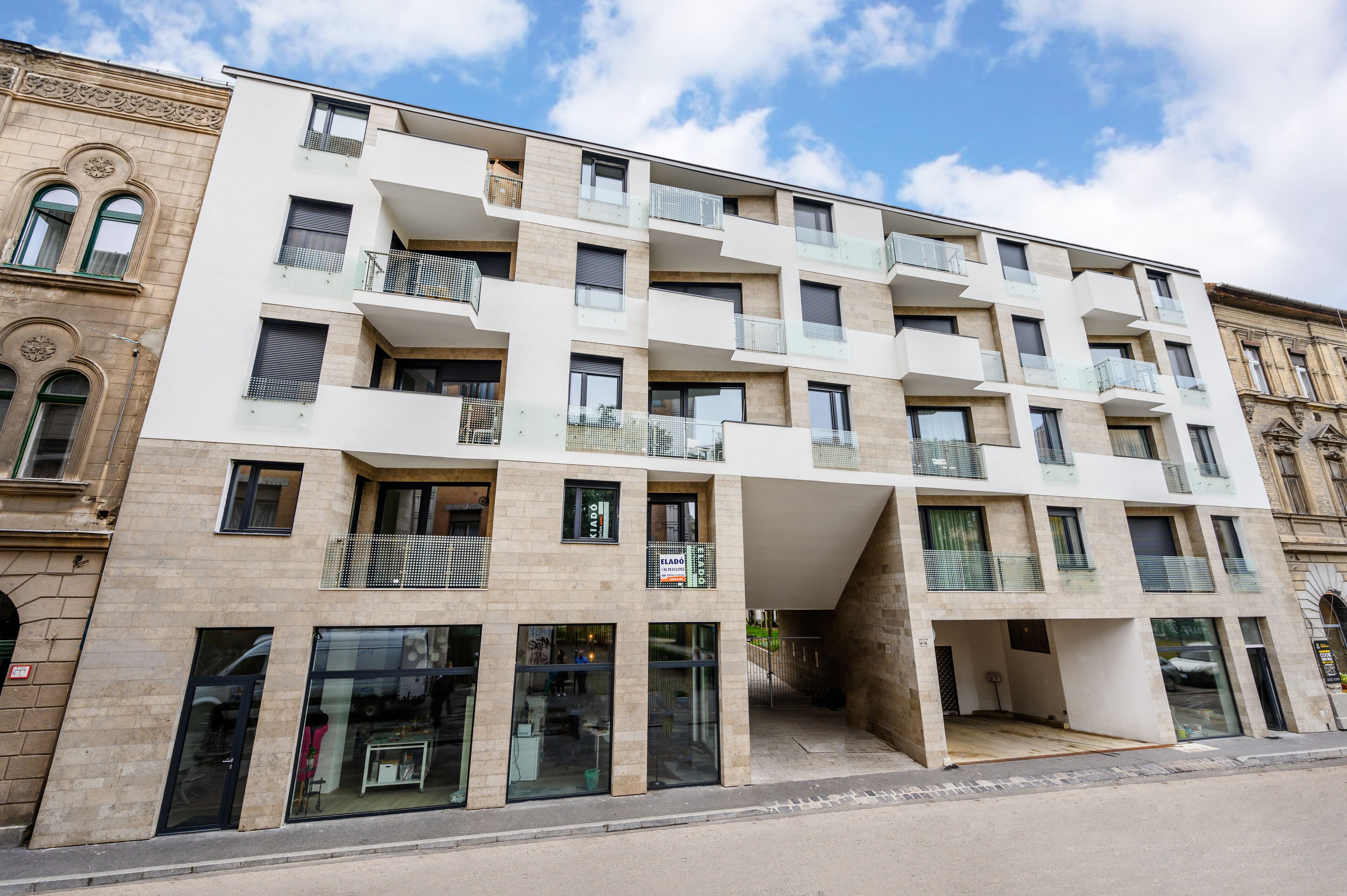 A multi-story building with a modern architectural style, featuring balconies, large windows, and a ground-level entrance.