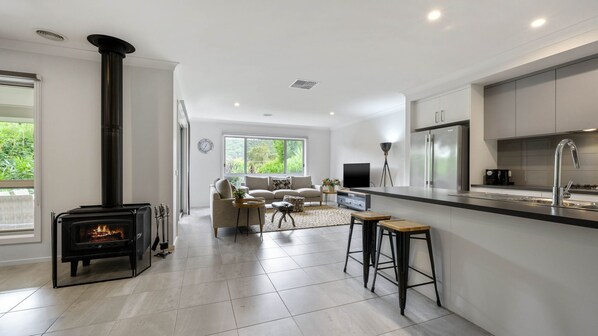 Cozy living area with a comfortable sofa and fireplace, complemented by a fully equipped kitchen with contemporary appliances.