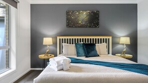 Relax in a spacious room with a large bed, two bedside tables, and a decorative piece above.