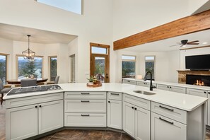 A modern kitchen with a large island, white cabinetry, and a fireplace.