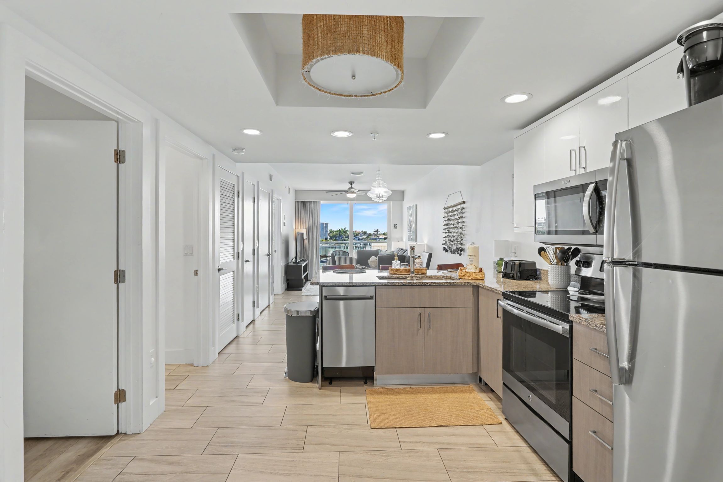 A modern kitchen with stainless steel appliances, a central island, and a view to the outside.