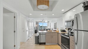 A modern kitchen with stainless steel appliances, a central island, and a view to the outside.