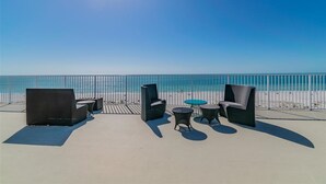 A beachside patio with outdoor furniture and a view of the ocean.