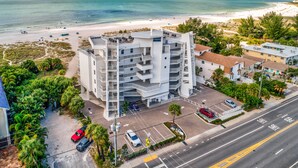 A multi-story hotel with a parking lot and a view of the beach.