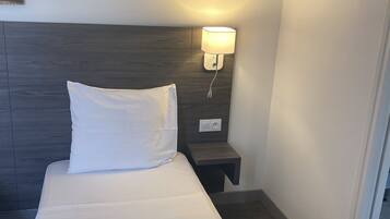 Habitación de hotel con cama, mesita de noche con lámpara, una obra de arte en la pared y un adorno mural.